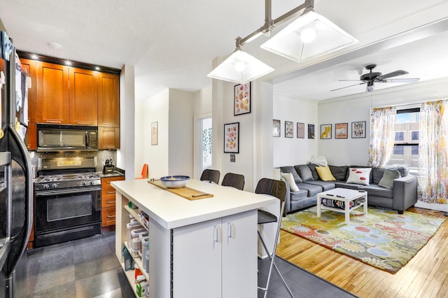 kitchen featuring black appliances, healthy amount of natural light, a kitchen bar, and a center island