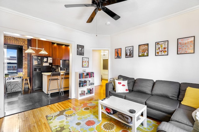 living area featuring ceiling fan, crown molding, and light wood-style flooring