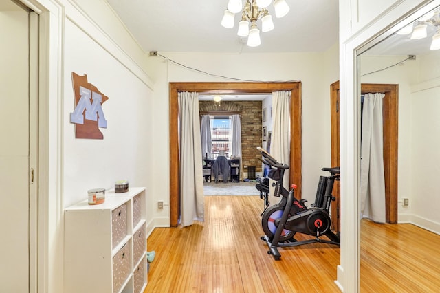 exercise area featuring a chandelier, light wood-style flooring, and baseboards