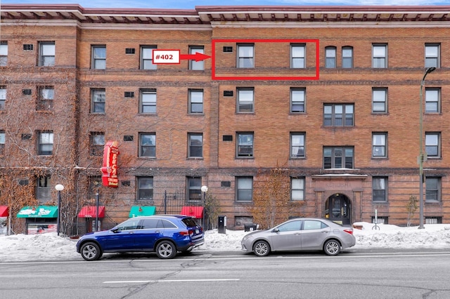 snow covered building featuring a view of apartment building / complex