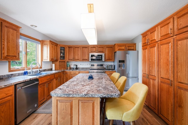 2806 Jasmine Ct, Saint Cloud, MN 56301 - kitchen with appliances with stainless steel finishes, a sink, light wood-style floors, a breakfast bar area, and a kitchen island