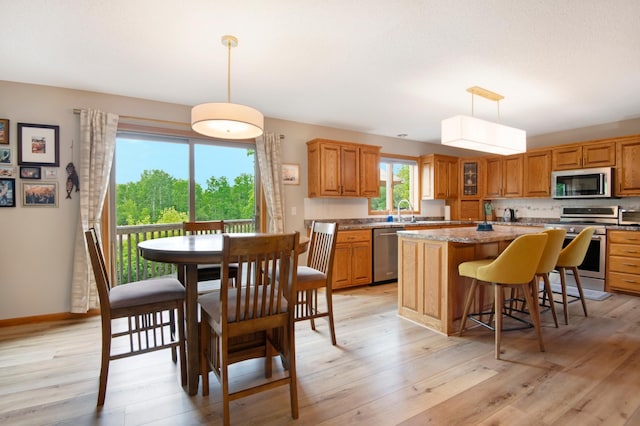 2806 Jasmine Ct, Saint Cloud, MN 56301 - kitchen featuring appliances with stainless steel finishes, a center island, a kitchen breakfast bar, and light wood-style floors
