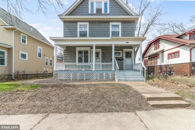 american foursquare style home featuring fence and covered porch