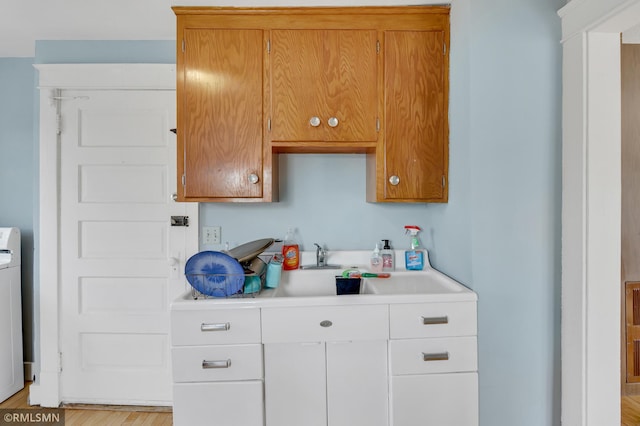 kitchen featuring brown cabinets, a sink, light wood-style floors, and light countertops
