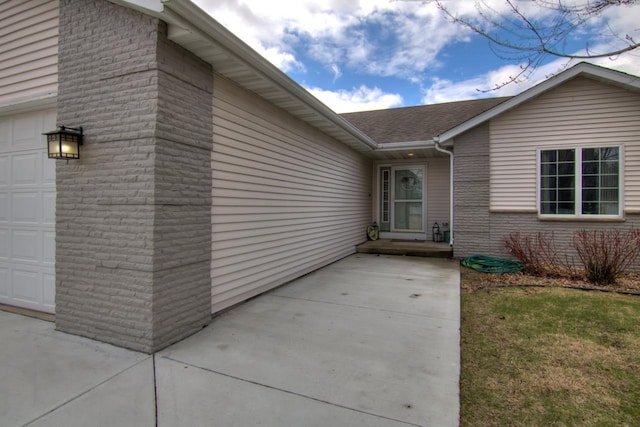 property entrance with an attached garage and roof with shingles