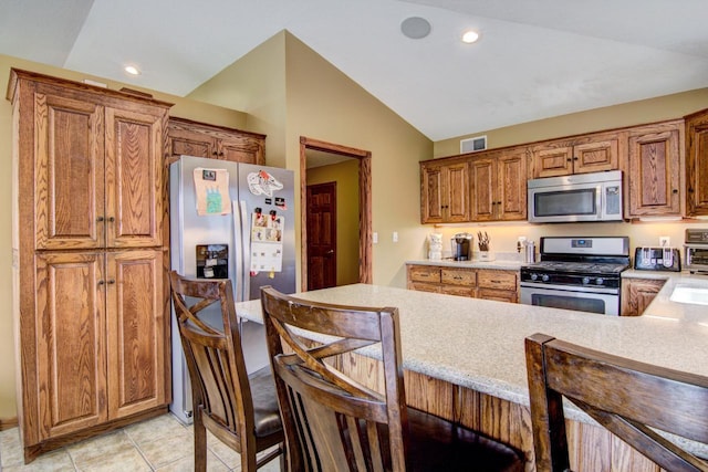 kitchen with a breakfast bar, stainless steel appliances, light countertops, lofted ceiling, and visible vents
