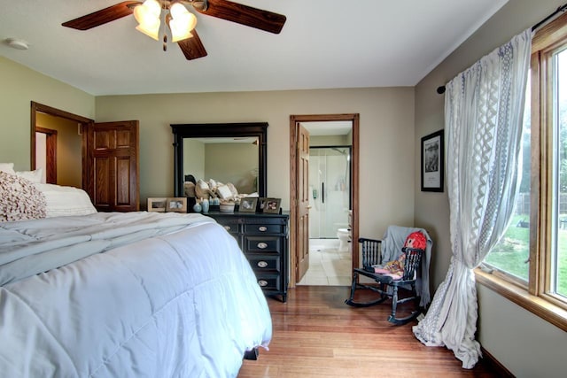 bedroom with wood finished floors, a ceiling fan, multiple windows, and ensuite bathroom