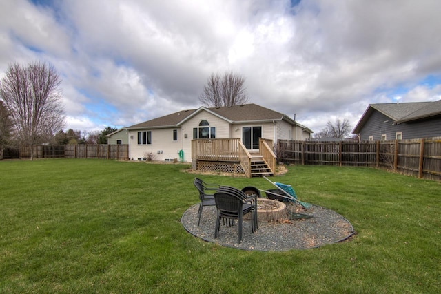 rear view of house with a lawn, a fenced backyard, an outdoor fire pit, and a deck