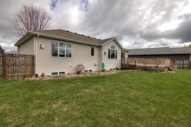 rear view of property with a wooden deck, a yard, and fence