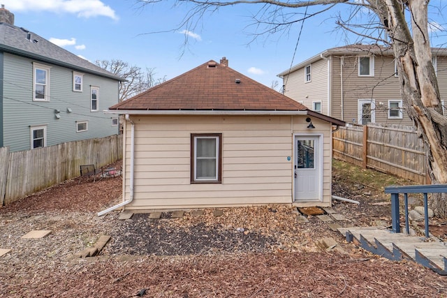 2943 Taylor St NE, Minneapolis, MN 55418 - rear view of house with a shingled roof, a fenced backyard, and a chimney