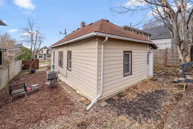 2943 Taylor St NE, Minneapolis, MN 55418 - view of side of property with central AC unit, roof with shingles, fence, and a chimney