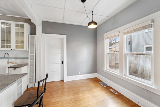 2943 Taylor St NE, Minneapolis, MN 55418 - unfurnished dining area with baseboards, visible vents, a sink, and light wood-style floors