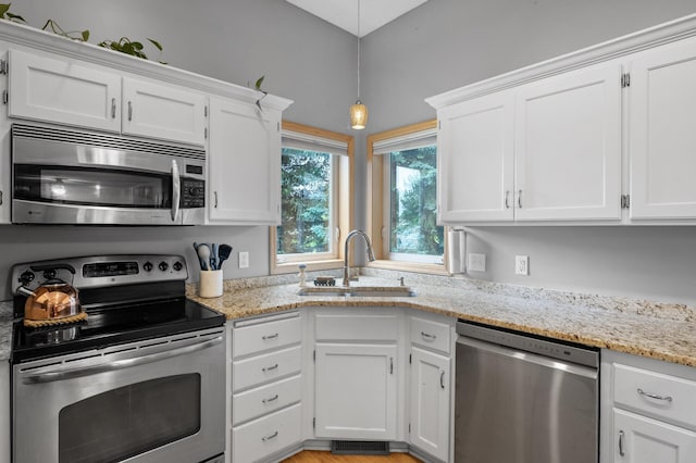 4032 Hollyhock Cir N, Brooklyn Park, MN 55443 - kitchen with appliances with stainless steel finishes, white cabinets, light stone countertops, and hanging light fixtures