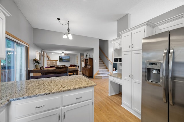 4032 Hollyhock Cir N, Brooklyn Park, MN 55443 - kitchen with stainless steel fridge, white cabinets, light wood-type flooring, light stone counters, and pendant lighting