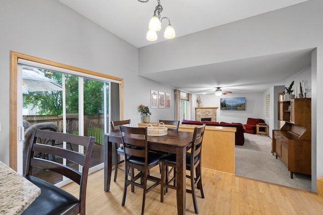 4032 Hollyhock Cir N, Brooklyn Park, MN 55443 - dining area with a fireplace, ceiling fan, and light wood-style floors