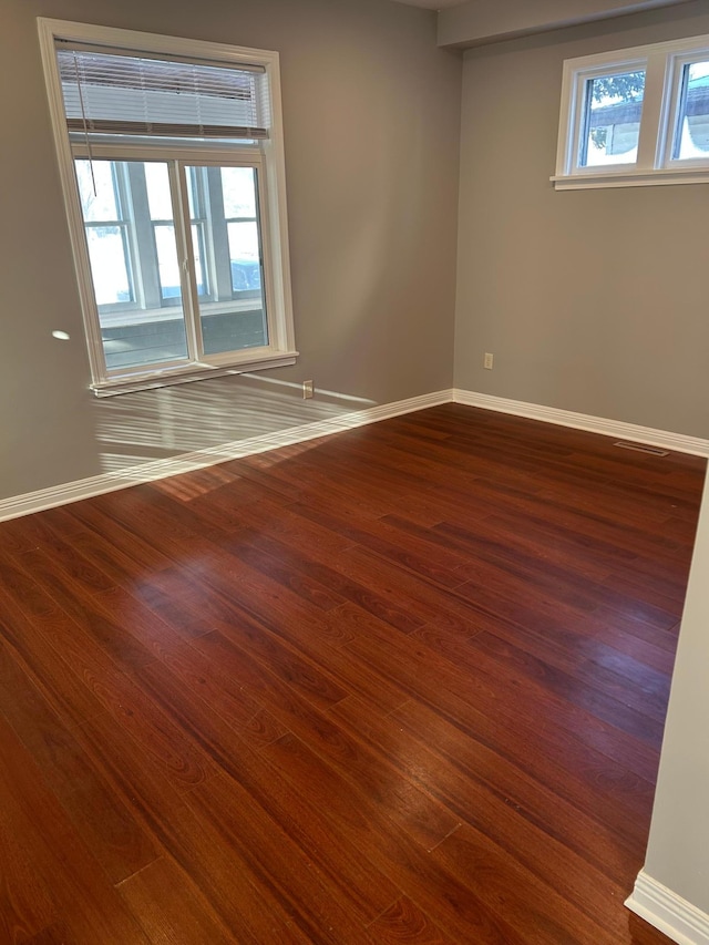empty room with baseboards, dark wood finished floors, and visible vents