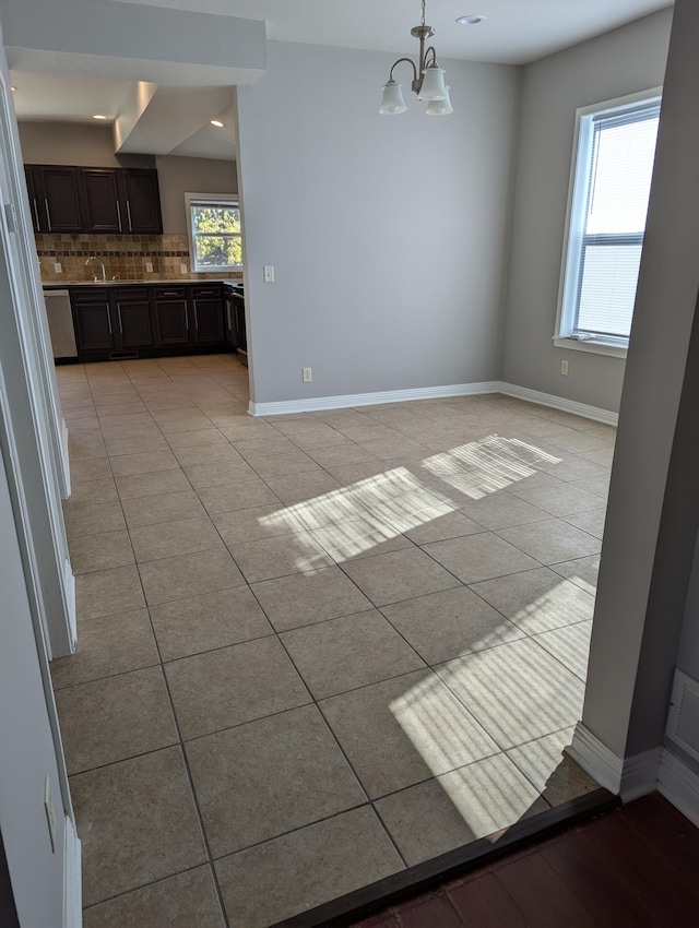 unfurnished dining area with baseboards, light tile patterned floors, and a chandelier