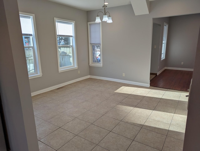 spare room with baseboards, a notable chandelier, and tile patterned flooring