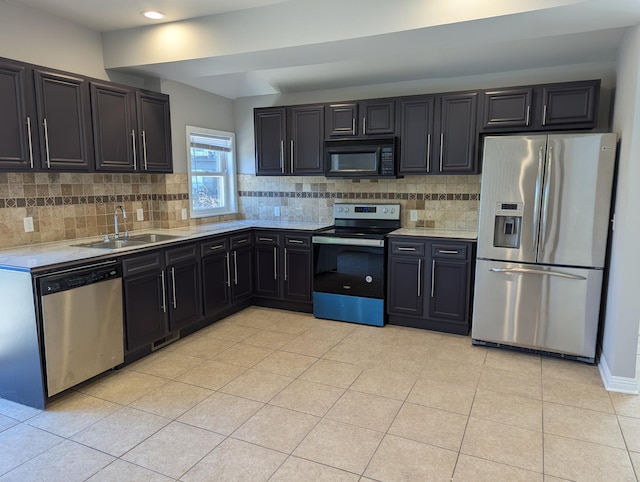 kitchen featuring light countertops, backsplash, appliances with stainless steel finishes, and a sink