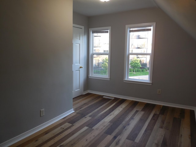 additional living space featuring baseboards, vaulted ceiling, dark wood-style floors, and a wealth of natural light