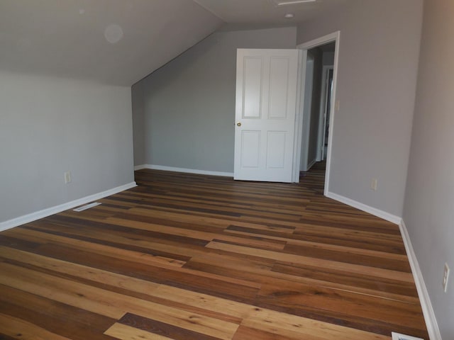 additional living space with baseboards, wood finished floors, and vaulted ceiling