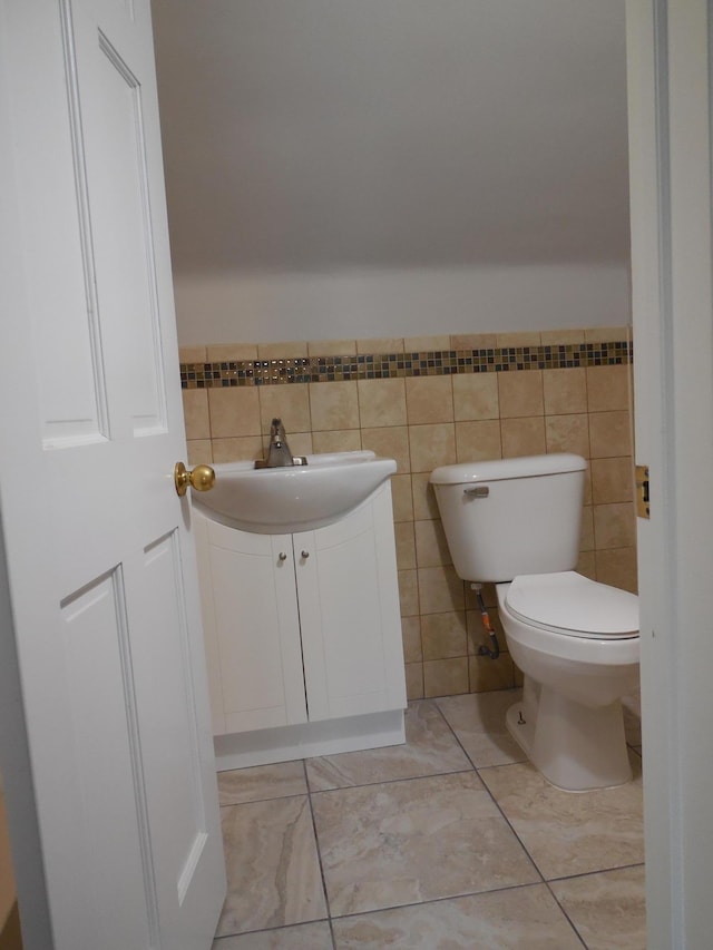 bathroom featuring vanity, toilet, and tile walls
