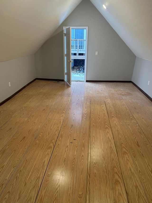 additional living space featuring baseboards, wood finished floors, and vaulted ceiling