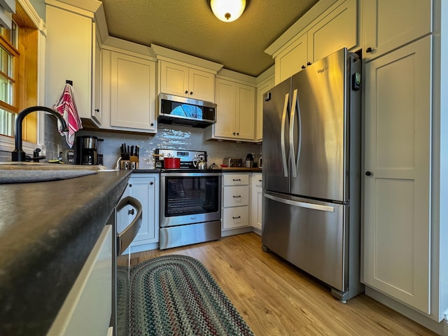 17783 Lookout Tower Rd NE, Hines, MN 56647 - kitchen featuring stainless steel appliances, dark countertops, light wood-style flooring, a sink, and backsplash