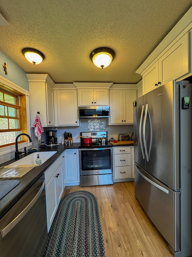 17783 Lookout Tower Rd NE, Hines, MN 56647 - kitchen featuring appliances with stainless steel finishes, extractor fan, light wood-type flooring, white cabinetry, and a sink
