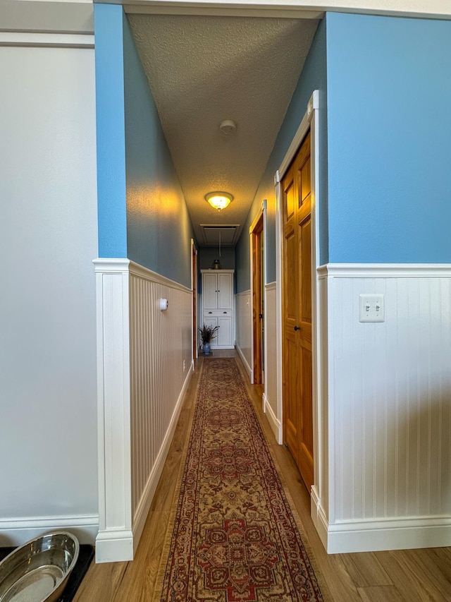 17783 Lookout Tower Rd NE, Hines, MN 56647 - corridor with attic access, wood finished floors, a wainscoted wall, and a textured ceiling