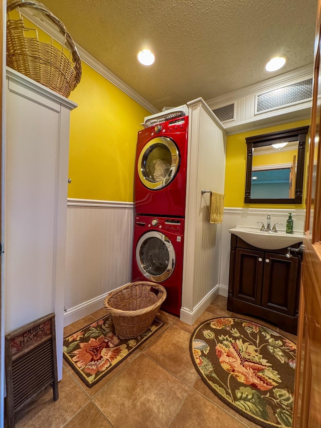 17783 Lookout Tower Rd NE, Hines, MN 56647 - laundry area featuring stacked washer and clothes dryer, a wainscoted wall, crown molding, a textured ceiling, and tile patterned floors