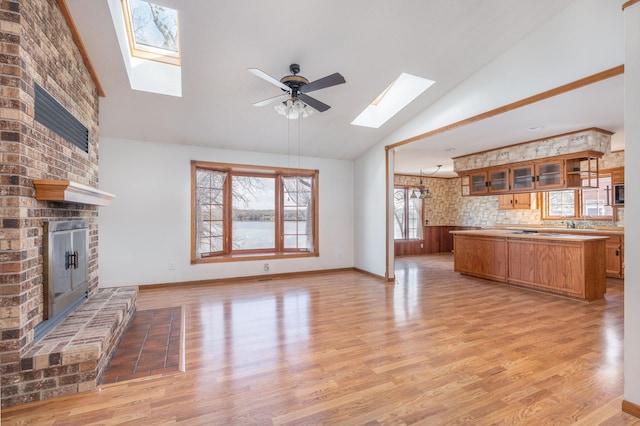 1122 Andrew Dr NE, Lake Andrew Twp, MN 56273 - unfurnished living room featuring a skylight, a brick fireplace, light wood-style floors, a ceiling fan, and high vaulted ceiling