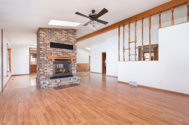 1122 Andrew Dr NE, Lake Andrew Twp, MN 56273 - unfurnished living room featuring a ceiling fan, a skylight, a fireplace, wood finished floors, and lofted ceiling