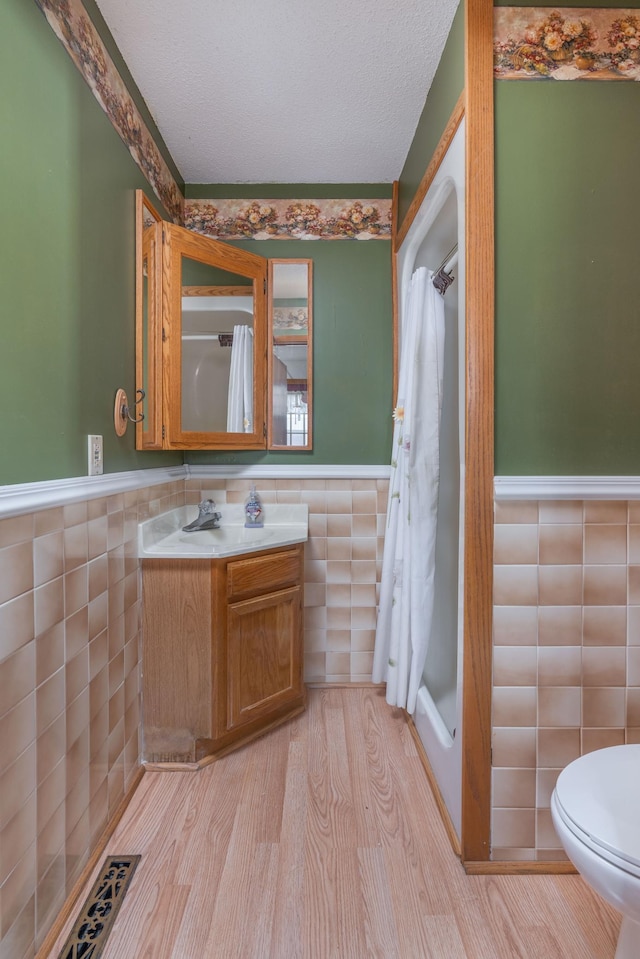 1122 Andrew Dr NE, Lake Andrew Twp, MN 56273 - bathroom featuring tile walls, a wainscoted wall, vanity, toilet, and wood finished floors