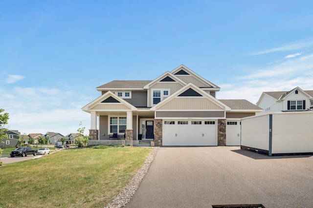 6674 Annabelle Ct, Corcoran, MN 55340 - view of front of property featuring stone siding, a front yard, board and batten siding, covered porch, and asphalt driveway