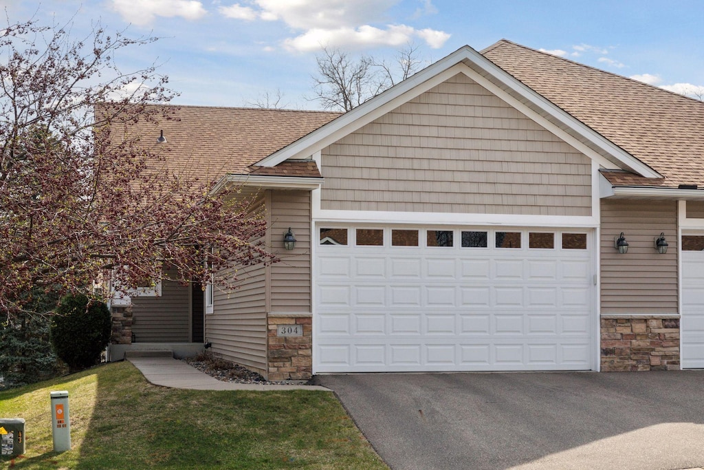 304 23rd Ct S, South Saint Paul, MN 55075 - view of front facade featuring stone siding, a shingled roof, and a garage