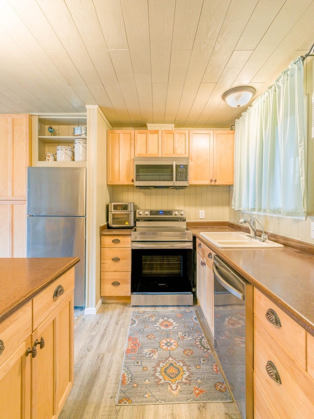 kitchen with light wood finished floors, light brown cabinetry, a toaster, a sink, and appliances with stainless steel finishes