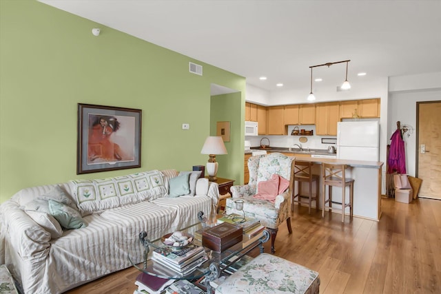 living room featuring light wood finished floors, visible vents, and recessed lighting
