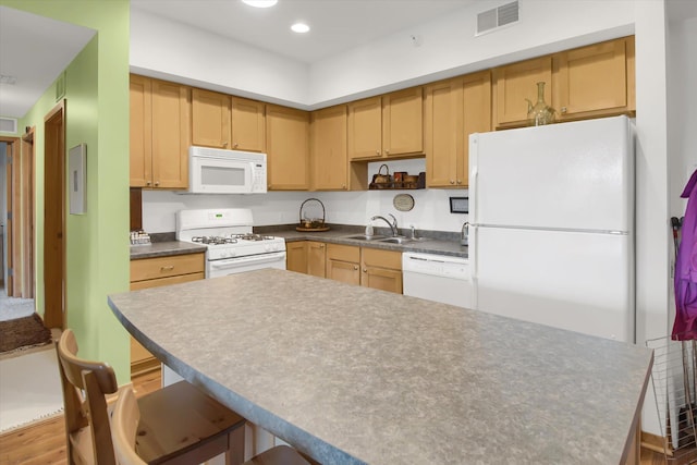 kitchen with dark countertops, wood finished floors, visible vents, a sink, and white appliances