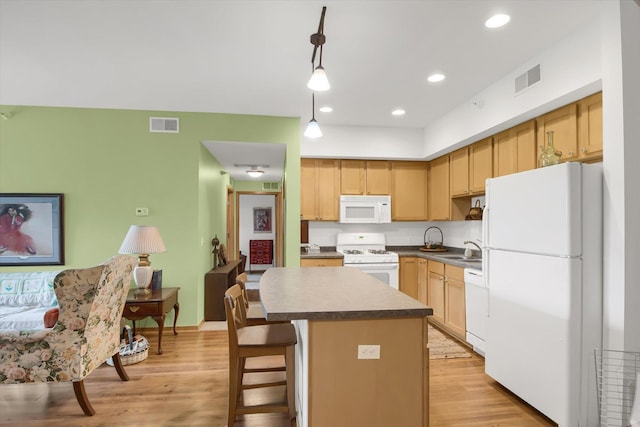 kitchen with visible vents, light brown cabinets, white appliances, and a sink