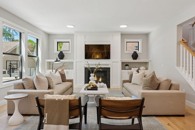 living area featuring light wood finished floors, stairway, a fireplace, baseboards, and recessed lighting