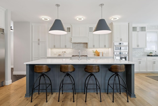 kitchen with stainless steel appliances, tasteful backsplash, a kitchen island with sink, and white cabinets