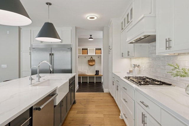 kitchen with appliances with stainless steel finishes, white cabinetry, backsplash, hanging light fixtures, and glass insert cabinets