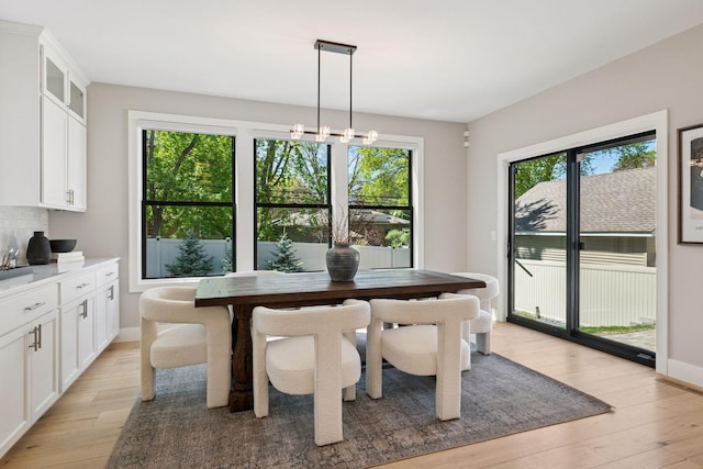 dining space with light wood-type flooring and baseboards