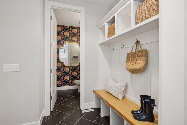 mudroom featuring wallpapered walls, baseboards, and dark tile patterned floors