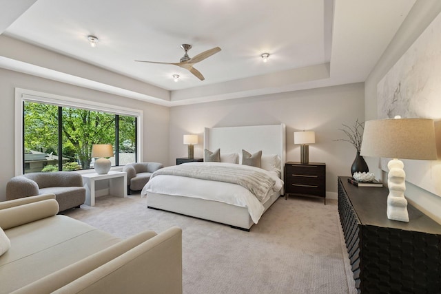bedroom featuring light carpet, a ceiling fan, and a raised ceiling