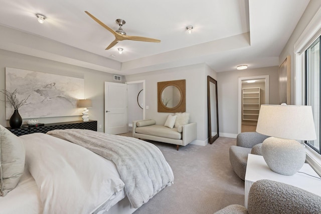 bedroom with light carpet, baseboards, a walk in closet, and ceiling fan