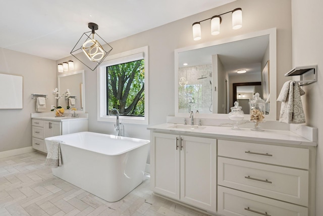 full bath featuring a stall shower, two vanities, a freestanding bath, and baseboards