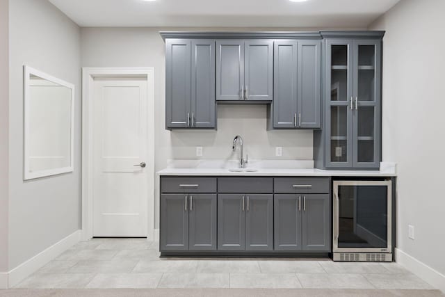 bar area with wine cooler, a sink, and baseboards