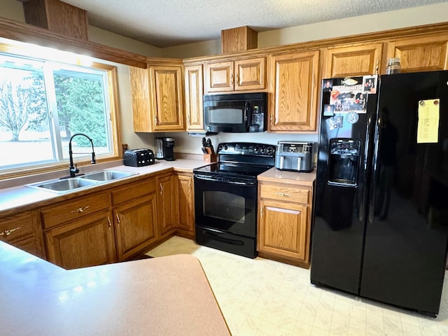 kitchen featuring light countertops, a sink, brown cabinets, and black appliances